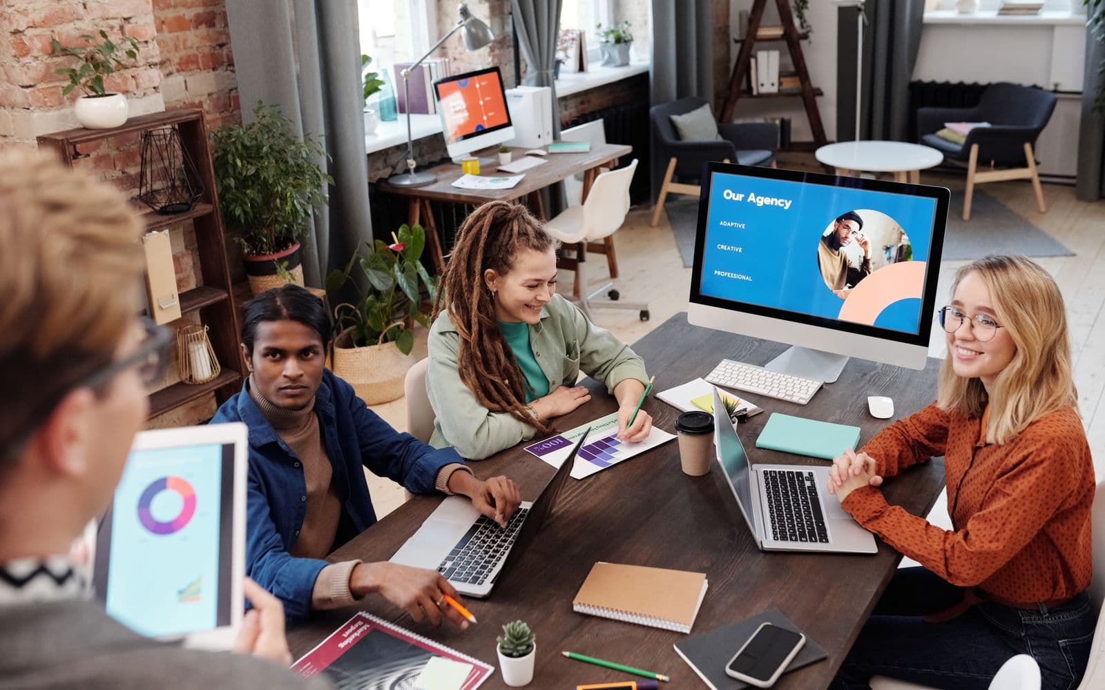 A small agency team working together around laptops in a studio