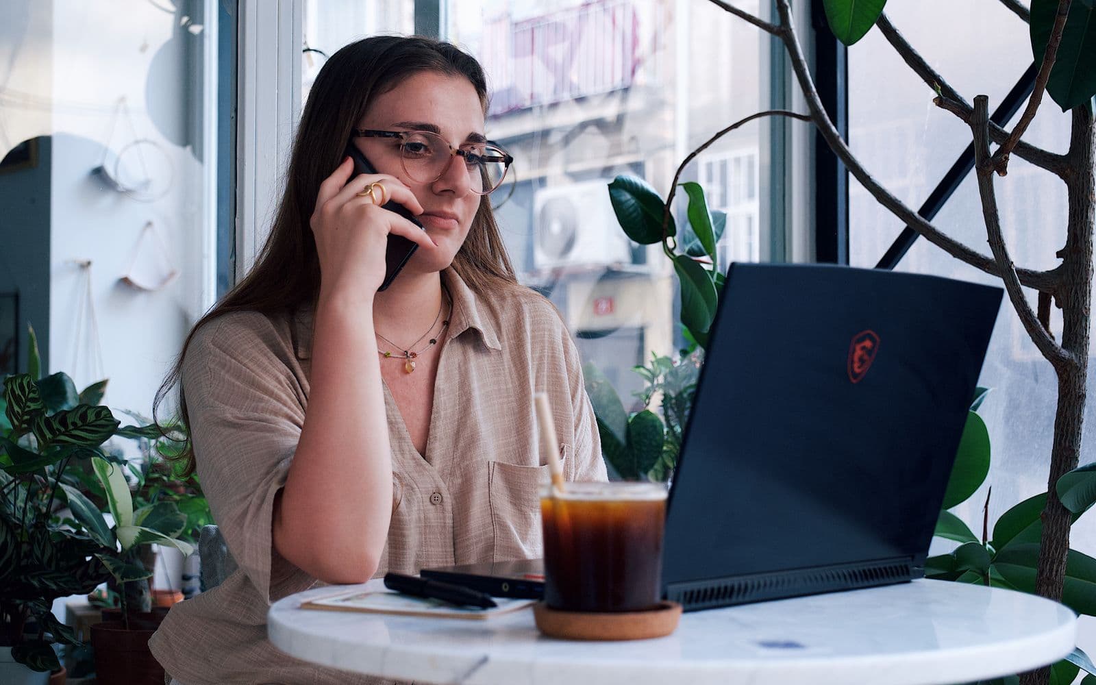 One person working from a laptop and taking a call away from an office
